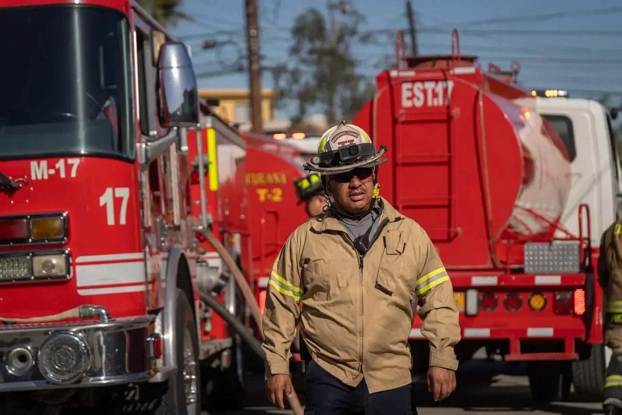 Bomberos realizan el rescate de una mujer atrapada en una vivienda en llamas.