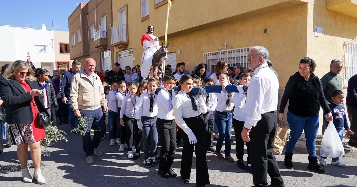 Niños y niñas de la hermandad llevan la "Burriquita" en una emotiva celebración del Domingo de Ramos.