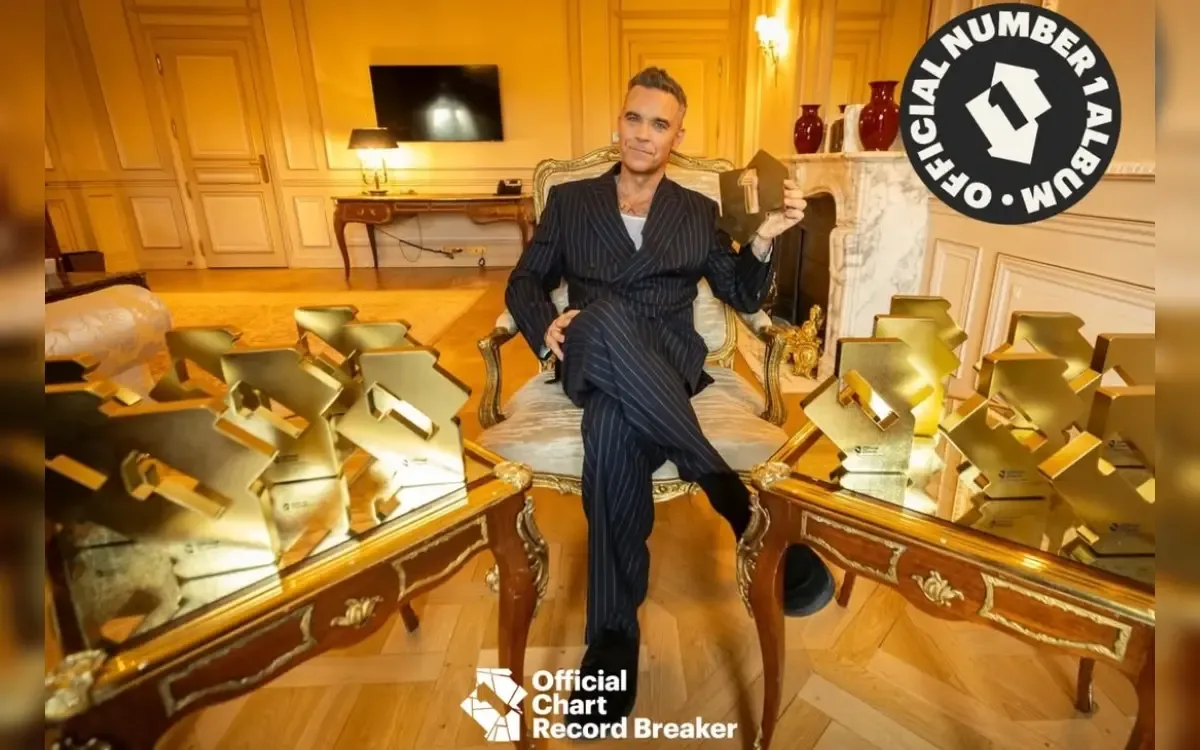 Robbie Williams celebrando su éxito musical tras romper el récord histórico en Reino Unido.